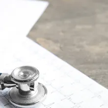 Stethoscope, red heart and cardiogram on gray table