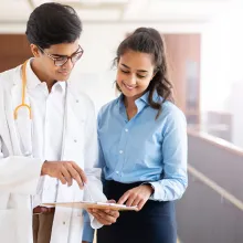 Image of doctor showing a medical professional a clip board.