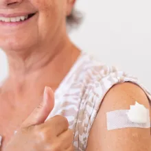 Senior woman smiling while showing her vaccine shot on arm
