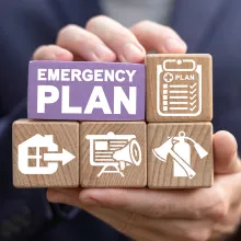 Hands holding wooden blocks with different icons and the words emergency plan