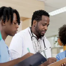 Male doctor and team of nurses reviewing clipboard in hospital