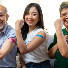 Family wearing bandaids flexing their arms after a vaccine 