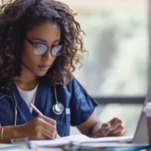 Clinician reading on laptop while taking notes