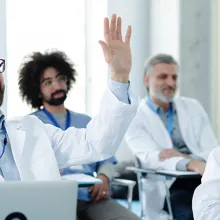 Clinicians in a learning setting, with one person raising their hand