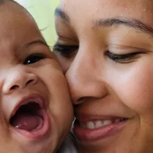 Mom cuddling smiling baby