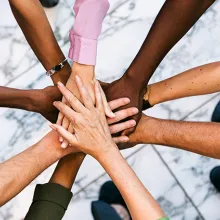 A group of individuals all putting their hand into a circle