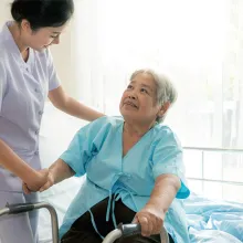 Nurse assisting senior woman getting out of hospital bed