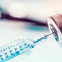 Close up image of a vaccine vial and a syringe