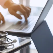 Medical professional with laptop and iPad on desk