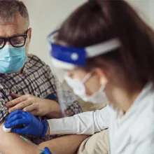 Medical professional administering vaccine shot to senior man