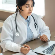 Clinician in front of a laptop sitting a desk