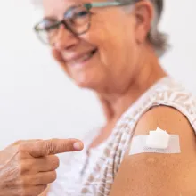 Senior smiling while showing a vaccine shot on arm