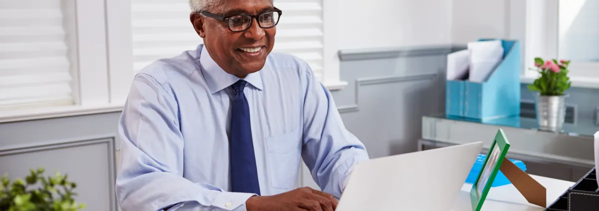 Senior black male doctor at work using laptop in an office