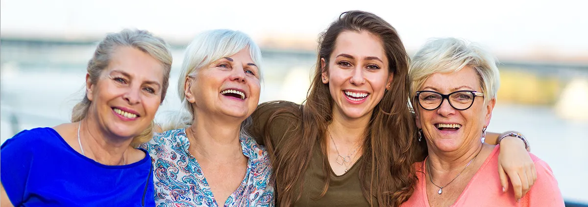 Two mothers and daughters standing together smiling