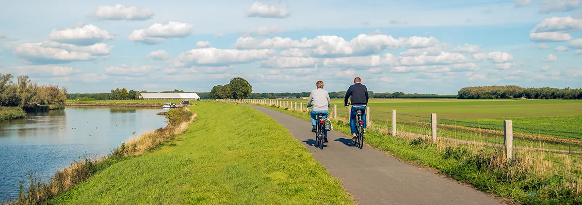 Two unidentified people cycle on a bike path