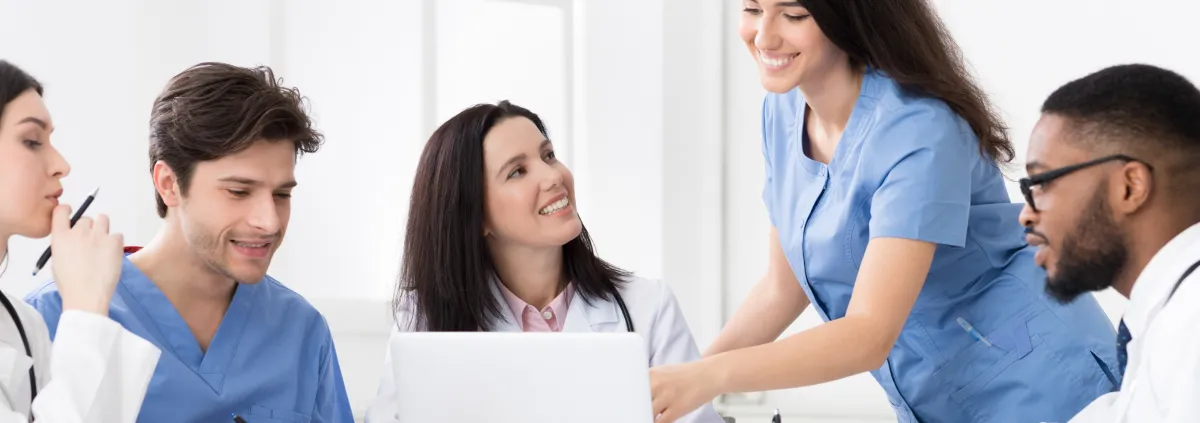 Practitioners and interns discussing medical reports on laptop