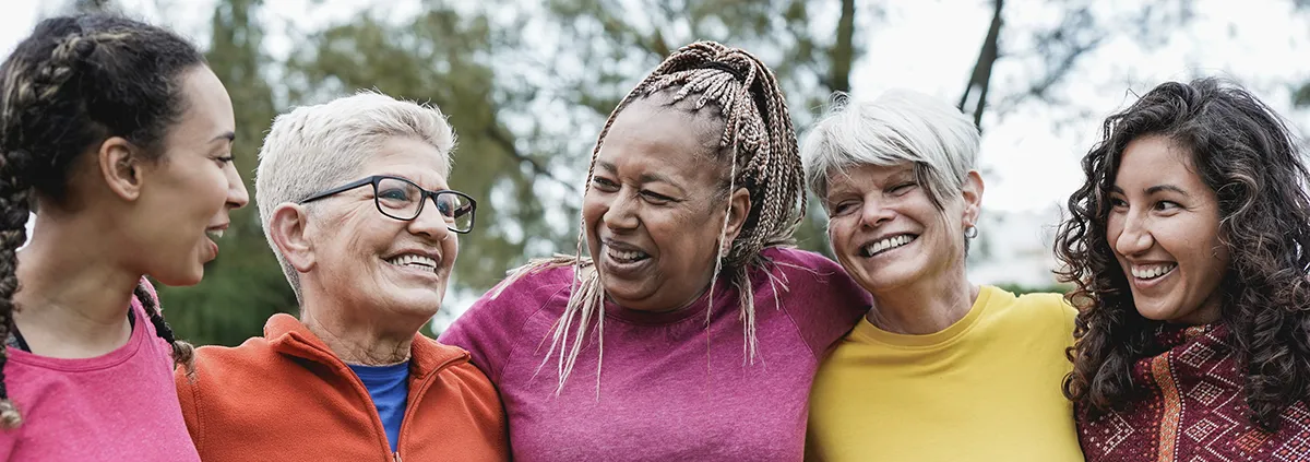 Group of smiling women wrapping arms around each other.