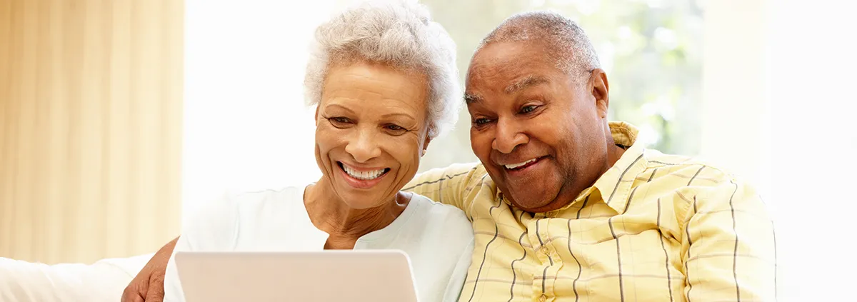 Male and female elder looking at laptop while sitting on couch