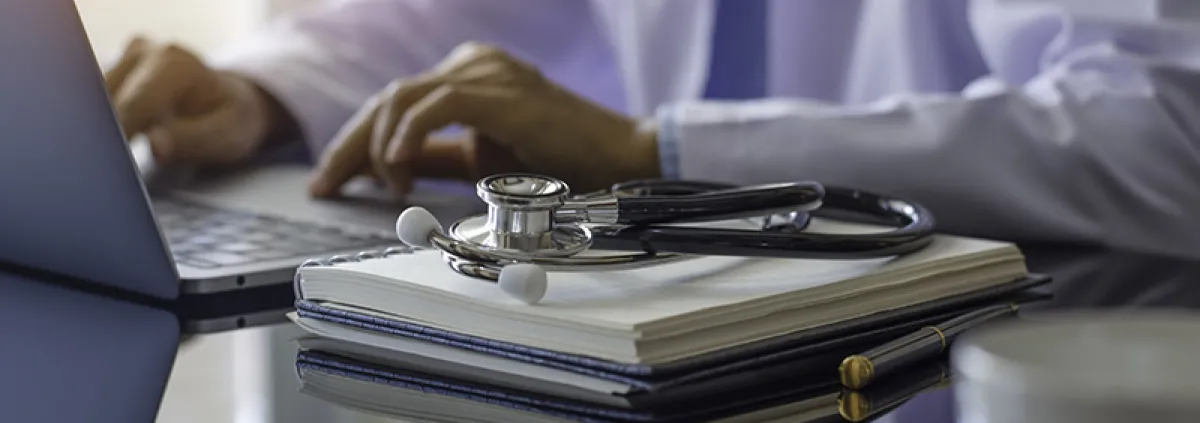 Doctor in white lab coat on laptop