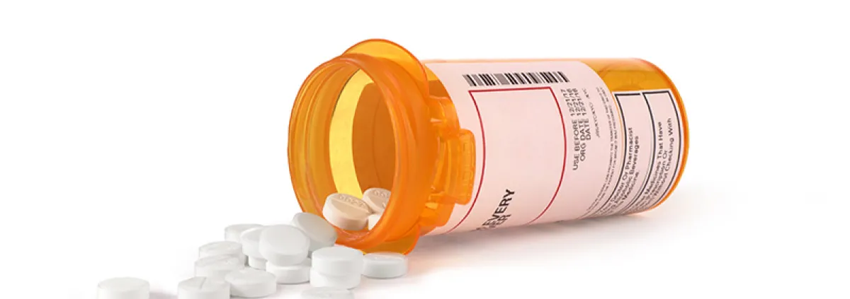 Image of white pills spilling out of a prescription bottle