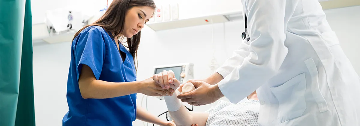 Female nurse and male nurse assisting elderly patient in hospital bed