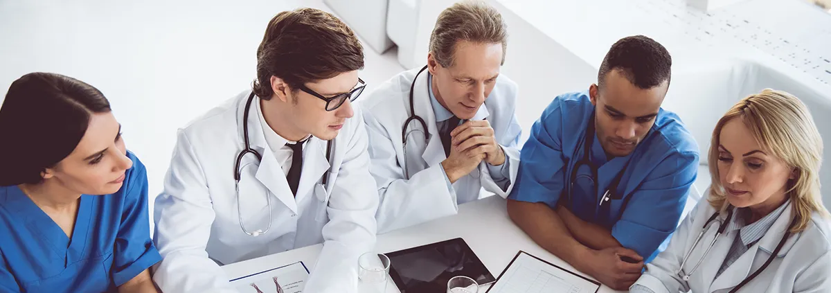 Female and male hospital staff in a discussion at a table.