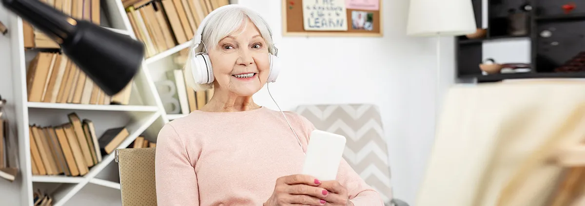 Elderly woman with headphones on sitting on couch