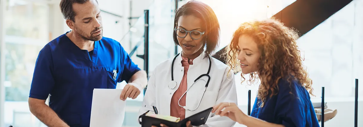 Two females and one male hospital staff in a discussion and looking at a document.