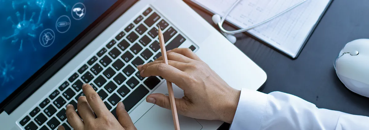 Person at laptop holding pencil