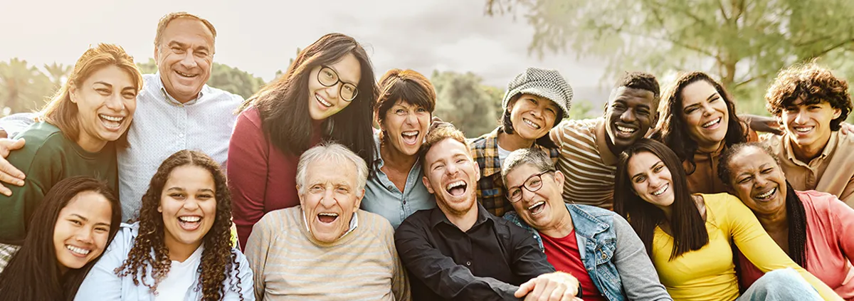 Happy multigenerational people having fun sitting on grass in a public park