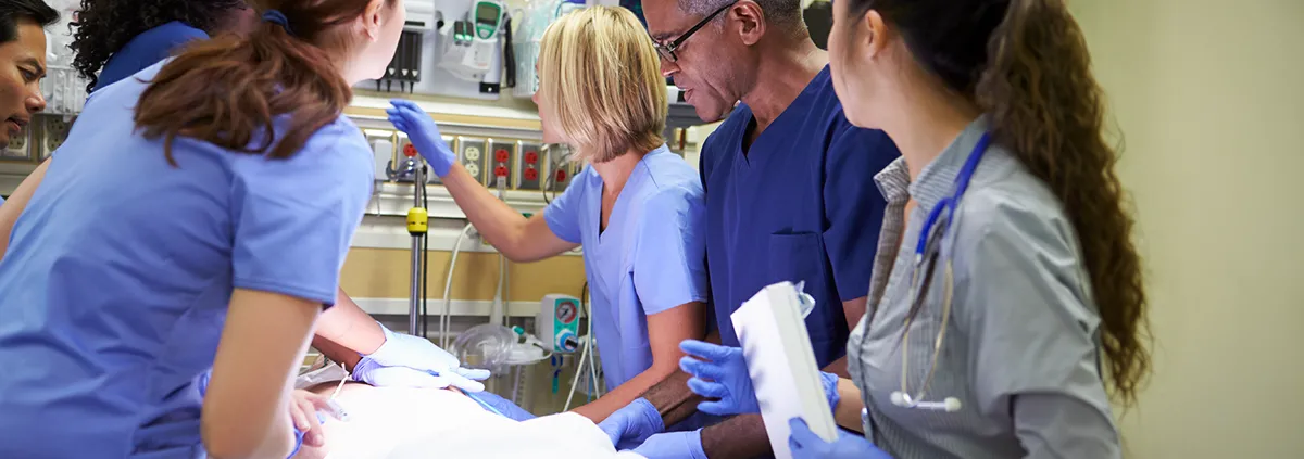 Nurses performing CPR and surrounding patient on hospital bed