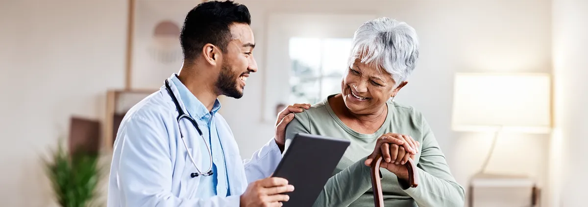 Male provider and female elderly patient sitting next to each other smiling