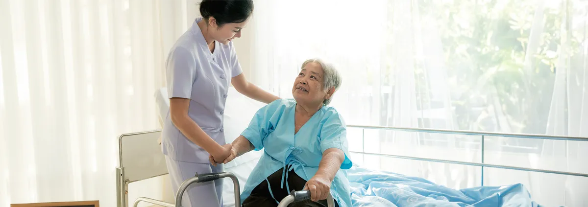 Image of female healthcare worker comforting a senior female in a nursing home environment.