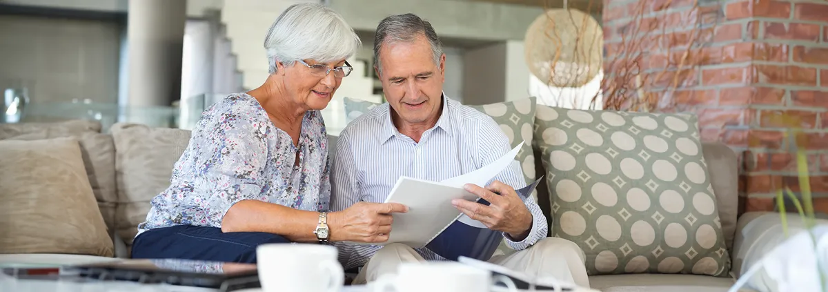 Elder couple reading papers together on a sofa