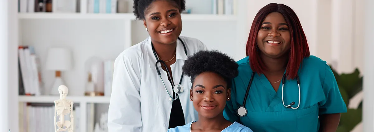 Three female healthcare workers smiling at the camera.