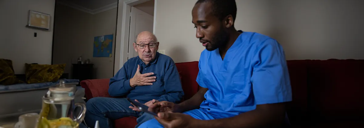 An elderly patient talks to medical professional during a home doctor visit.