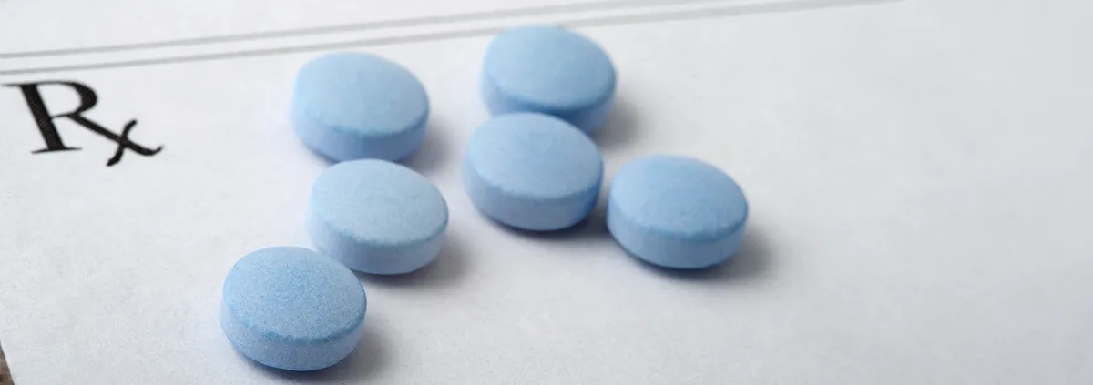 Round Blue Pills Spread Out on a Blank Prescription Form.