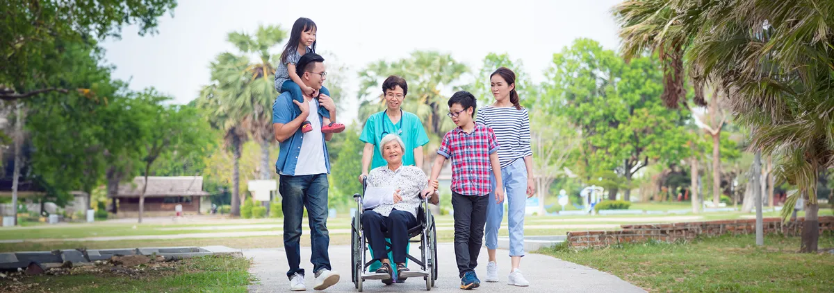 Caregiver pushing wheelchair surrounded by patient's family