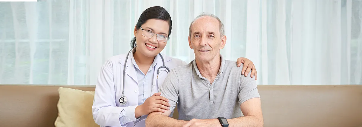Image of Asian doctor on the left with her arms around an older white male.