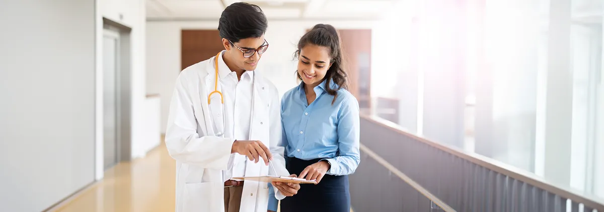 Image of doctor showing a medical professional a clip board.