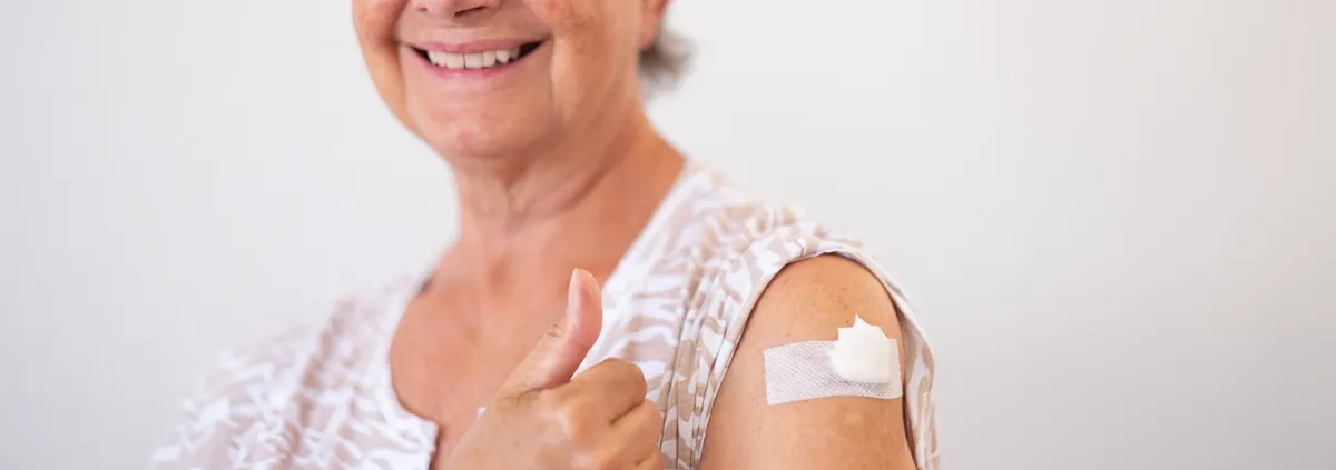 Senior woman smiling while showing her vaccine shot on arm