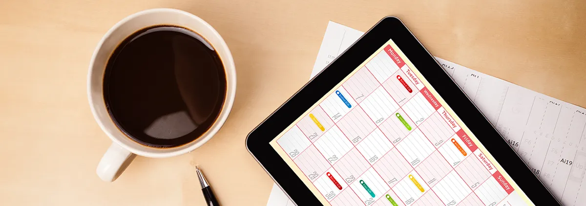 electronic calendar sitting next to a cup of coffee 