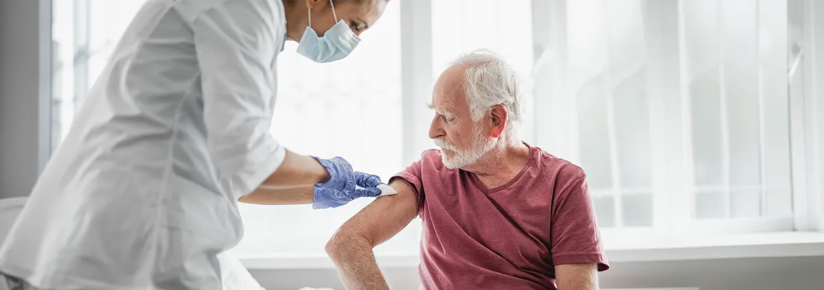 Senior man receiving vaccination from medical professional