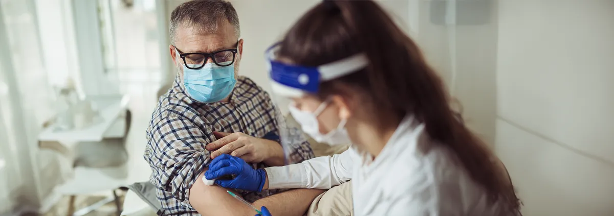 Medical professional administering vaccine shot to senior man