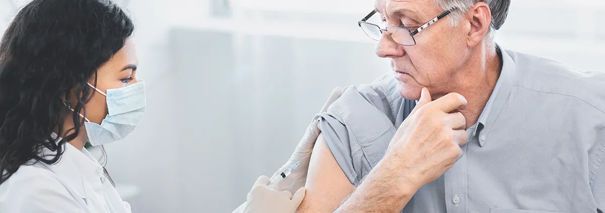 Nurse administering COVID-19 vaccine to senior man 