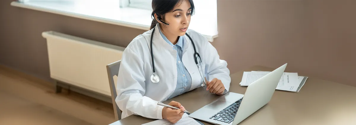 Clinician in front of a laptop sitting a desk