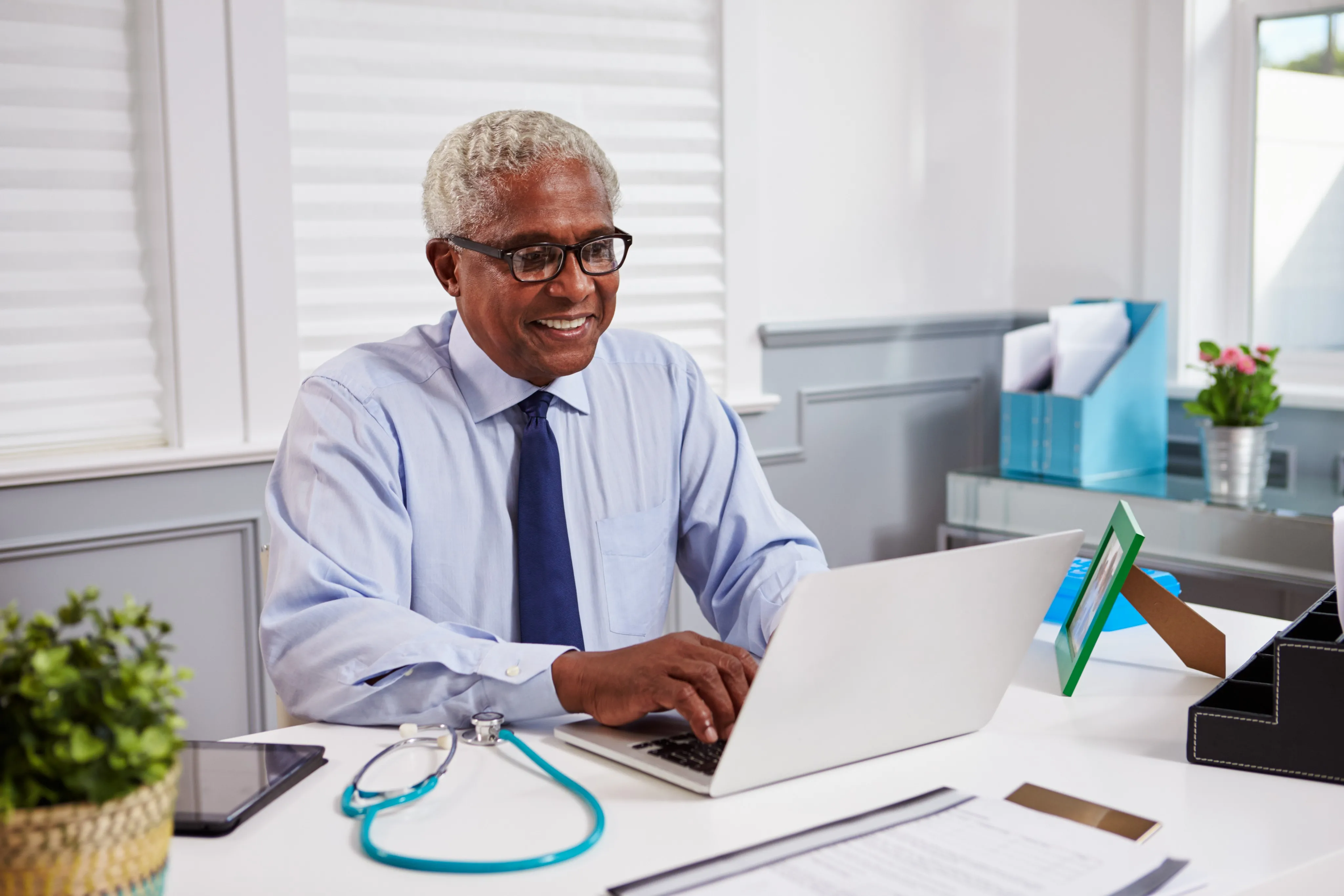 Senior black male doctor at work using laptop in an office