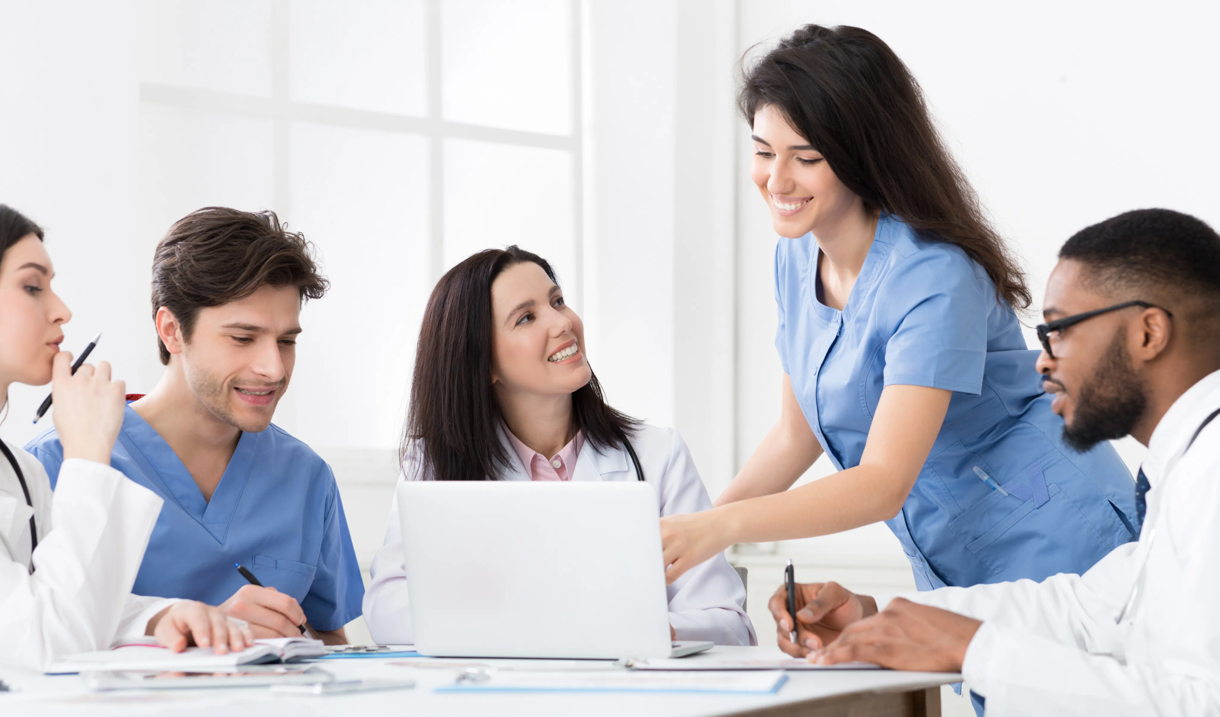 Practitioners and interns discussing medical reports on laptop