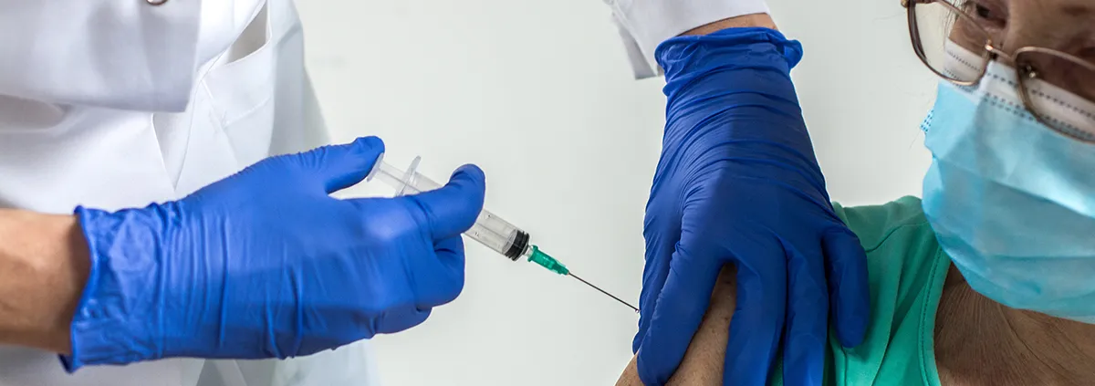 Clinician giving a senior woman a vaccination.