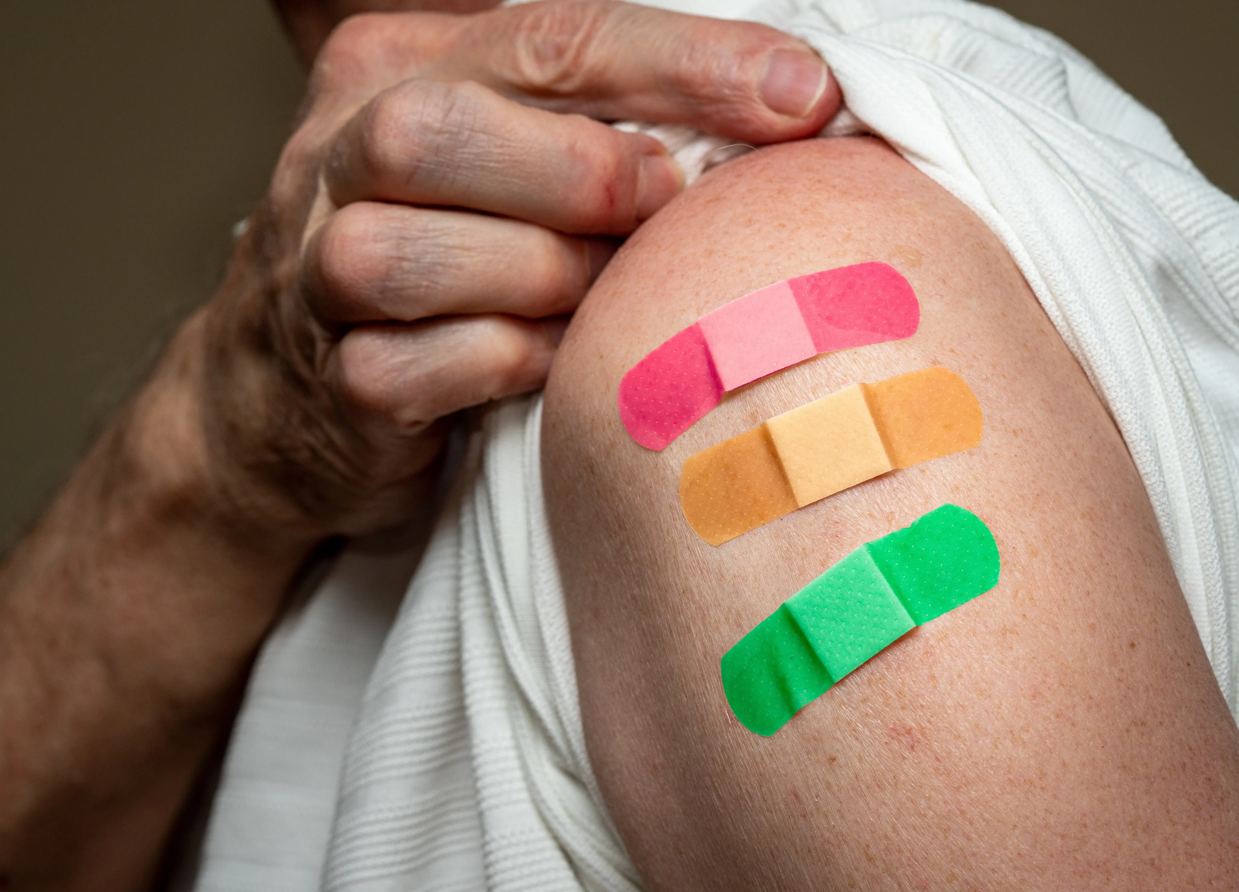 Senior caucasian man sleeve to show the third booster coronavirus vaccine shot in the shoulder.